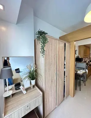 a room with a wooden cabinet and a desk with a lamp at Luxury staycation at prime location Mall of Asia Shell Residences Pasay Tower C in Manila