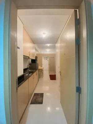 a kitchen with white cabinets and a hallway at Light Residence Condo with Pool View in Manila