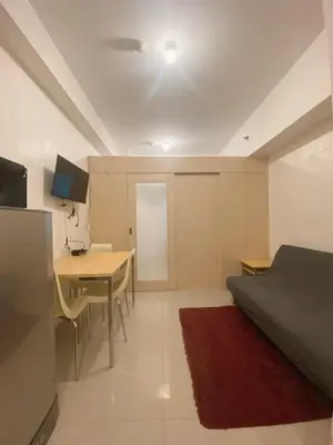 a room with a bed and a table and a desk at Light Residence Condo with Pool View in Manila