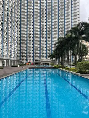a large blue swimming pool in front of a large building at Light Residence Condo with Pool View in Manila