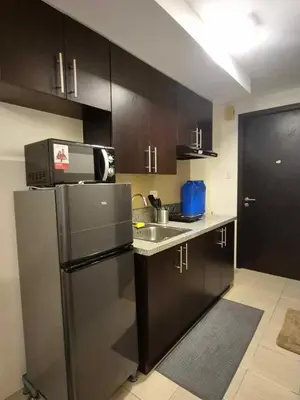 a kitchen with black cabinets and a stainless steel refrigerator at B&C Studio Kasara Urban Resort Residences in Manila