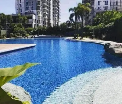 a large blue swimming pool with buildings in the background at B&C Studio Kasara Urban Resort Residences in Manila