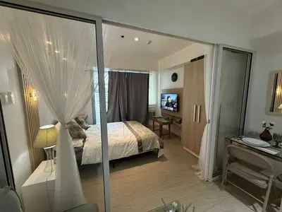 a bedroom with a bed and a desk with a computer at AZURE BICUTAN POSITANO Tower in Manila