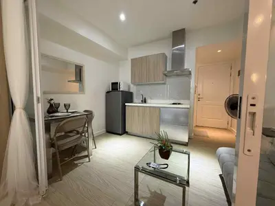 a kitchen and a living room with a table at AZURE BICUTAN POSITANO Tower in Manila