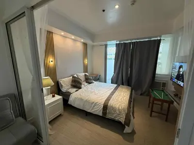 a bedroom with a bed and a desk and a window at AZURE BICUTAN POSITANO Tower in Manila