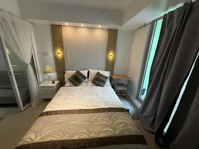 a bedroom with a large bed and a large window at AZURE BICUTAN POSITANO Tower in Manila