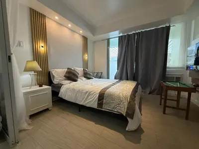 a bedroom with a bed and a table and a window at AZURE BICUTAN POSITANO Tower in Manila