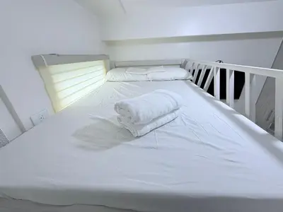 a white bed with two towels on top of it at Michaels Cozy Retreat in Cubao in Manila