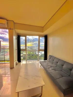 a living room with a couch and a table at Breeze Deluxe moa view 6pax in Manila