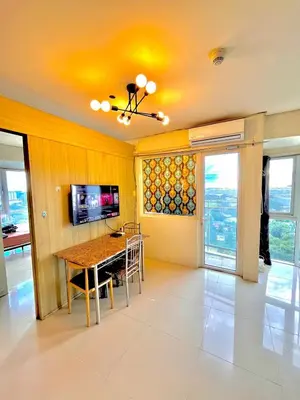 a dining room with a table and a television at Breeze Deluxe moa view 6pax in Manila