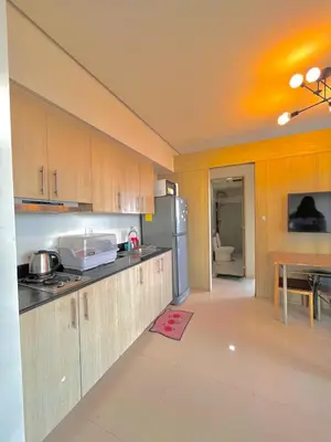 a kitchen with wooden cabinets and a counter top at Breeze Deluxe moa view 6pax in Manila