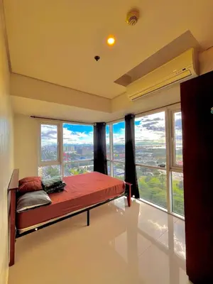 a bedroom with a bed in a room with large windows at Breeze Deluxe moa view 6pax in Manila