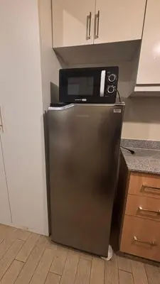 a microwave sitting on top of a refrigerator in a kitchen at DH Suites in Manila