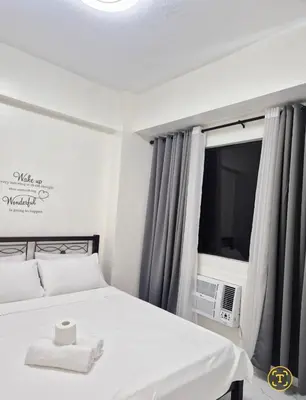a bedroom with a white bed and a television at Modern Minimalist 1BR Condotel at BGC Taguig in Taguig