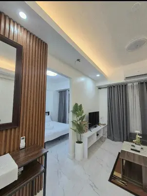 a living room with a room with a bed and a television at Modern Minimalist 1BR Condotel at BGC Taguig in Taguig