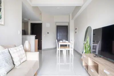 a living room with a white couch and a television at Uptown Parksuites BGC Stylish 2BR Fast WiFi Washer Balcony in Manila