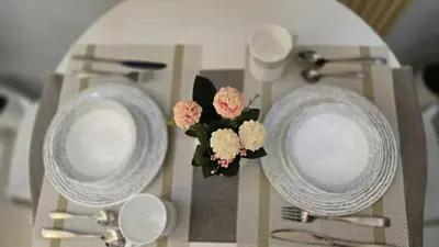 two plates and a vase of flowers on a table at Sheena's Suite by Staycation in Manila