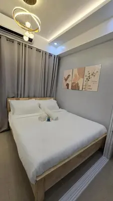 a bedroom with a large bed with white sheets and a chandelier at Sheena's Suite by Staycation in Manila