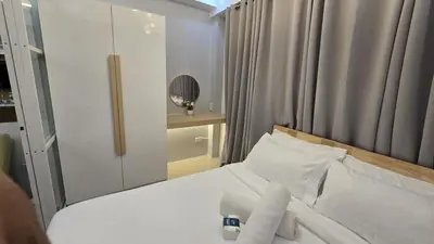 a bedroom with a white bed and a mirror at Sheena's Suite by Staycation in Manila