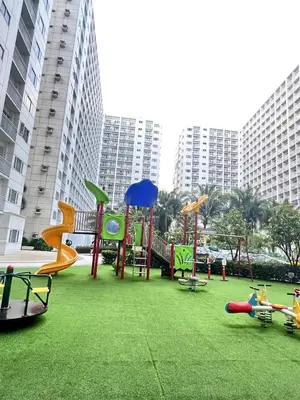 a playground in a park with grass and buildings at Sheena's Suite by Staycation in Manila
