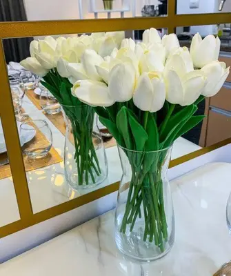 three vases filled with white flowers on a table at Hometel by ECR at Viceroy Residences in Manila