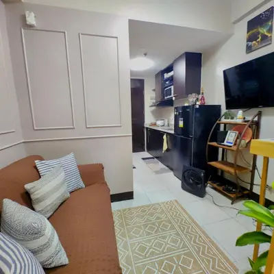 a living room with a couch and a flat screen tv at 1BR Cozy Home with Balcony Near NAIA Terminals in Manila