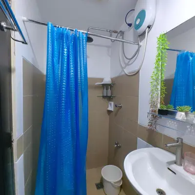 a bathroom with a blue shower curtain and a sink at 1BR Cozy Home with Balcony Near NAIA Terminals in Manila