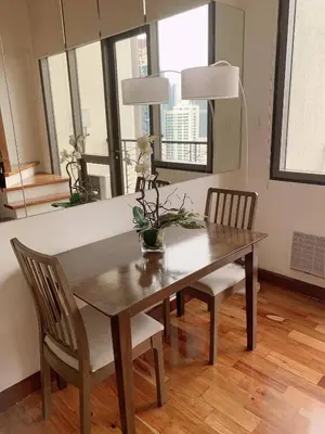 a dining room table with two chairs and a table with flowers on it at Modern Makati Condo for Rent - City Views Convenience in Manila