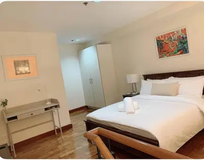 a bedroom with a large bed and a desk at Modern Makati Condo for Rent - City Views Convenience in Manila