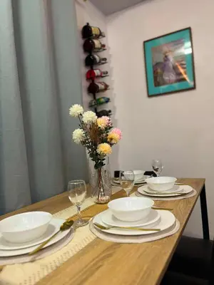 a table with plates and glasses and a vase of flowers at Balai Sais - Your Scenic Home Away from Home! in Binangonan