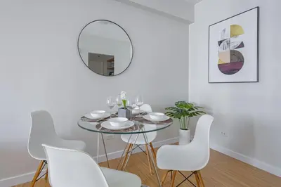 a dining room with a round mirror and white chairs at 1 BR Central and Cozy Condo Prime Location in BGC in Manila