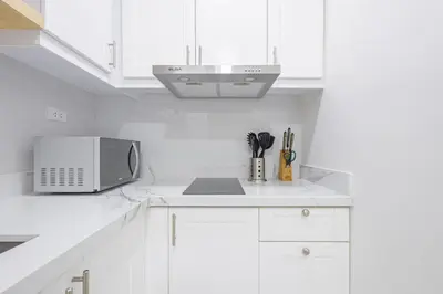 a kitchen with white cabinets and a microwave at 1 BR Central and Cozy Condo Prime Location in BGC in Manila