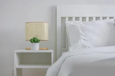 a bedroom with a white bed and a nightstand with a plant at 1 BR Central and Cozy Condo Prime Location in BGC in Manila