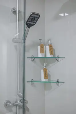 a glass shelf in a shower with three toiletries at 1 BR Central and Cozy Condo Prime Location in BGC in Manila