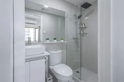 a bathroom with a toilet and a sink and a shower at 1 BR Central and Cozy Condo Prime Location in BGC in Manila