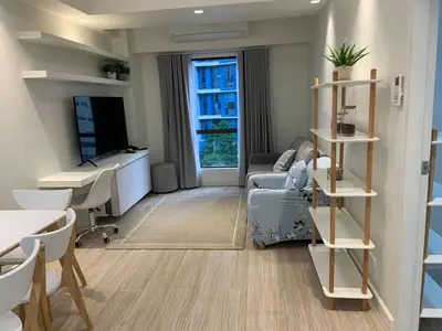 a living room with a couch and a table and a desk at Comfy and Renovated 1 BR with Balcony BGC Golf View in Manila