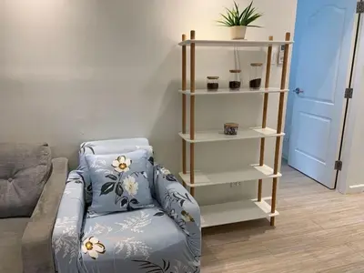 a living room with a couch and a shelf at Comfy and Renovated 1 BR with Balcony BGC Golf View in Manila