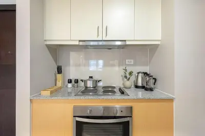 a kitchen with a stove and white cabinets at Stylish 2 BR Home with Bathtub and Balcony Uptown BGC in Manila