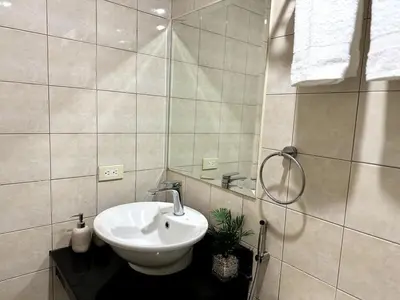 a bathroom with a white sink and a shower at Modern Luxe 3 BR Home BGC in Manila