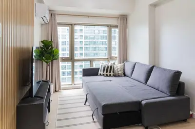 a living room with a couch and a large window at Scandi 1 BR Home Golf View BGC in Manila