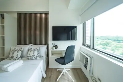 a bedroom with a bed and a chair and a tv at Scandi 1 BR Home Golf View BGC in Manila