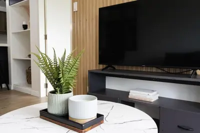 a living room with a tv and a potted plant at Scandi 1 BR Home Golf View BGC in Manila