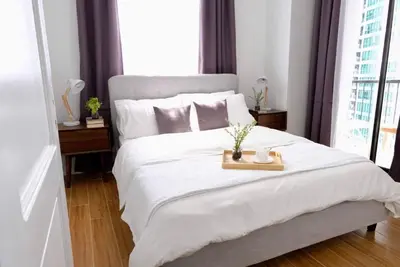 a bedroom with a white bed with a tray on it at Golf Penthouse Balcony BGC in Manila