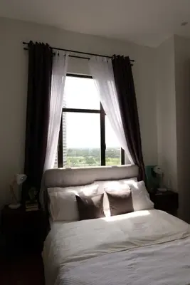 a bedroom with a large bed with a window at Golf Penthouse Balcony BGC in Manila