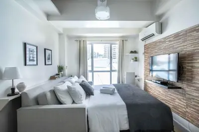 a bedroom with a large bed and a tv at Julias Bright Stylish Condo Balcony in Manila