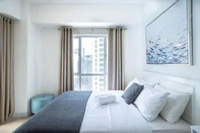 a bedroom with a white bed with a large window at Julias Bright Stylish Condo Balcony in Manila