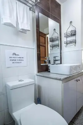 a bathroom with a toilet and a sink and a mirror at Julias Bright Stylish Condo Balcony in Manila