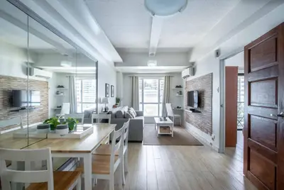 a dining room and living room with a table and chairs at Julias Bright Stylish Condo Balcony in Manila