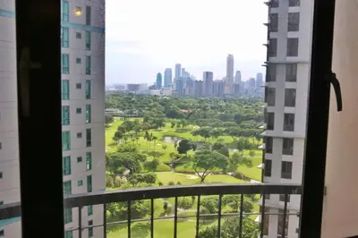 a view of a park from a window in a building at Julias Attractive and Cozy Penthouse Golf View in Manila