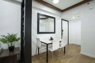 a dining room with a table and chairs and a mirror at Julias Contemporary Apt Balcony and Golf View in Manila